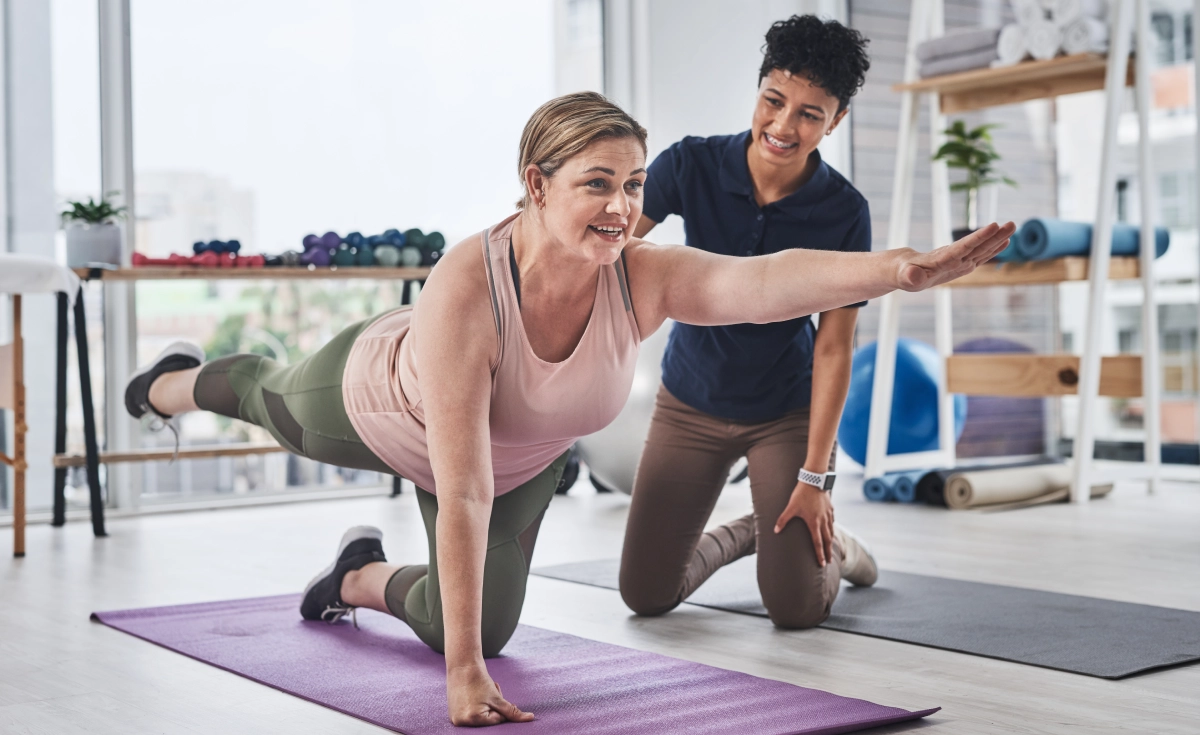 Woman doing a yoga pose with trainer.